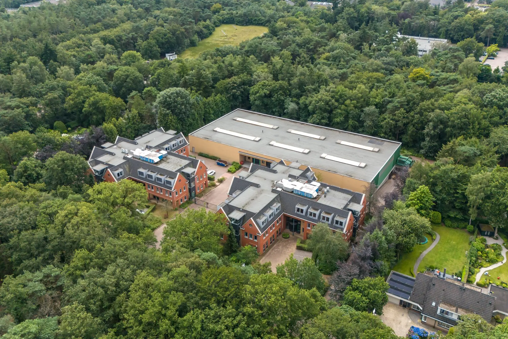 Luchtfoto van gebouwen aan de Laan Blussé van Oud-Alblas, omringd door dichtbegroeid bosgebied.